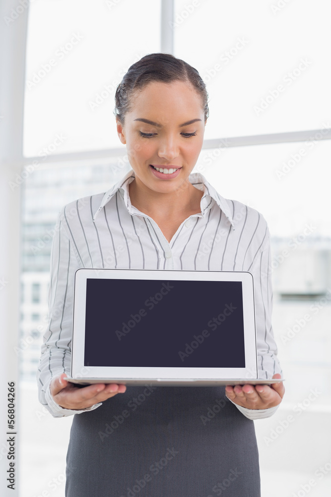 Smiling businesswoman showing laptop screen and looking at it