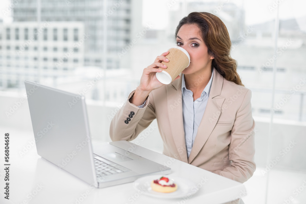 Businesswoman drinking coffee at her desk in front of laptop Businesswoman drinking coffee at her desk in front of laptop