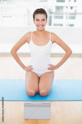Cute natural brown haired woman in white sportswear posing with