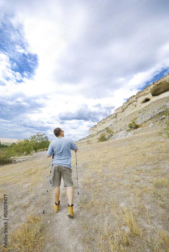 Adult man is hiking with trekking poles