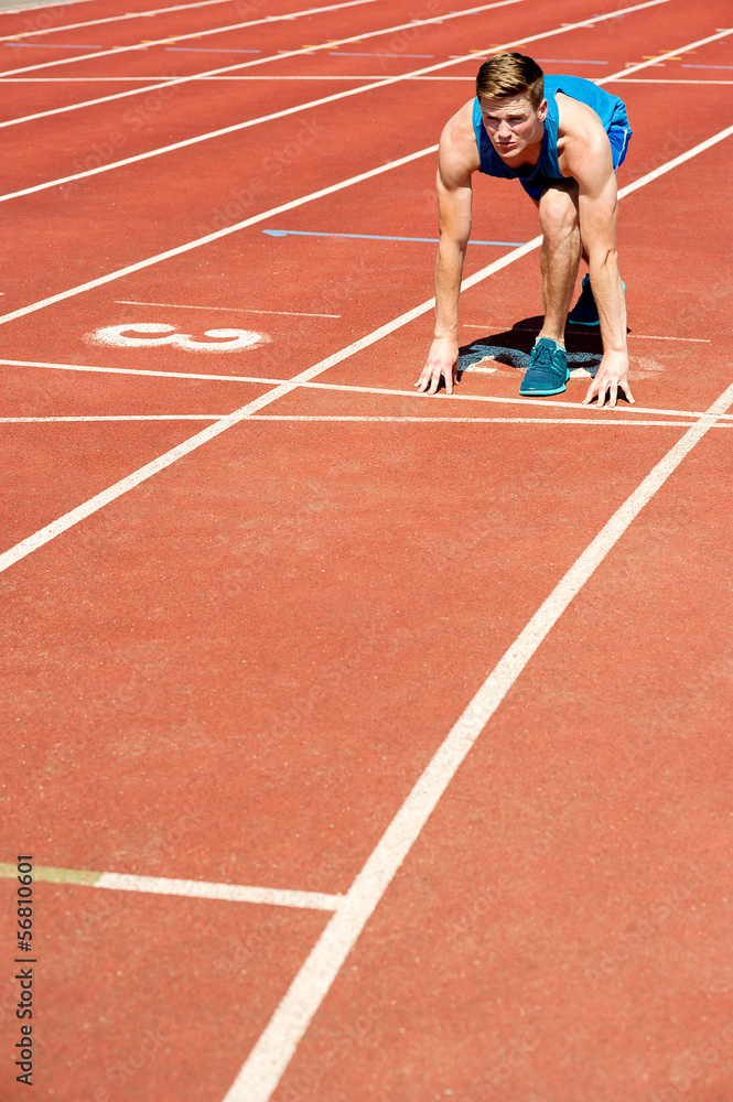 Athletic man on track, all set for race.