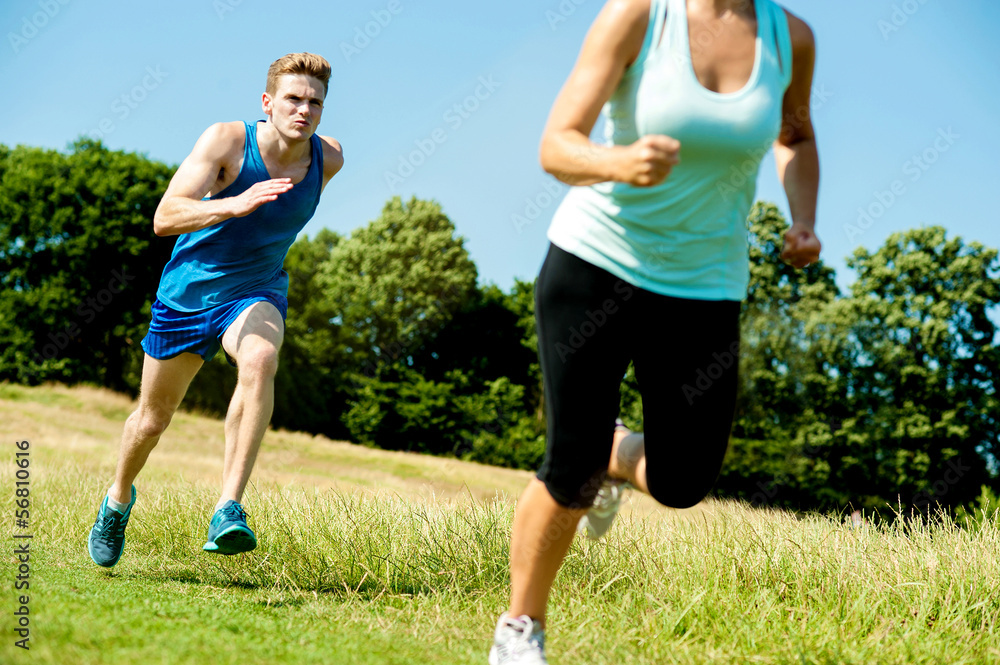 Two athletes running through meadows Two athletes running through meadows