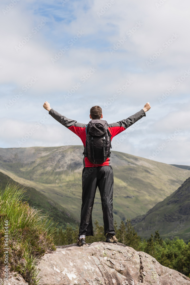 Man standing at hill top cheering