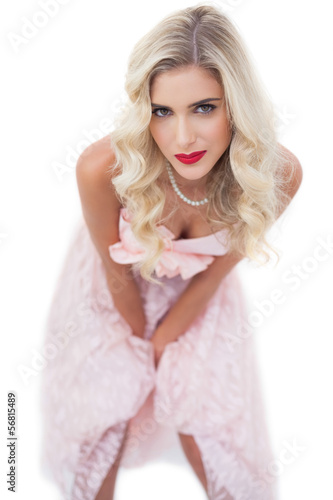 Pretty blonde model in pink dress posing hands on the thighs