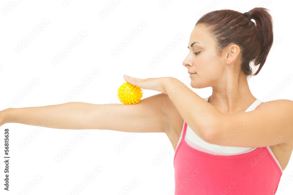 Peaceful sporty brunette touching arm with yellow massage ball Peaceful sporty brunette touching arm with yellow massage ball