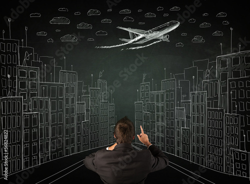 Businessman sitting in front of a cityscape drawing on a chalkbo