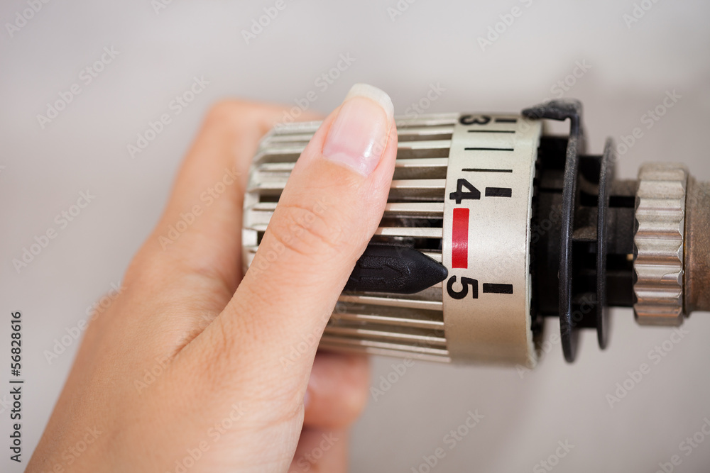 Woman Adjusting The Thermostat Woman Adjusting The Thermostat