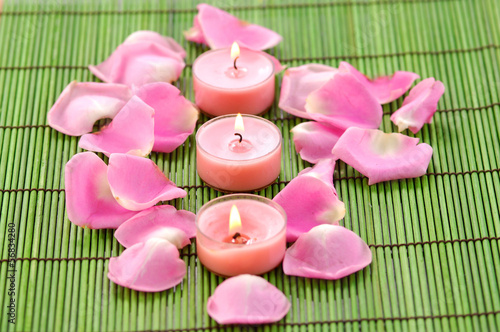 Spa composition of pile of rose petals and row candle