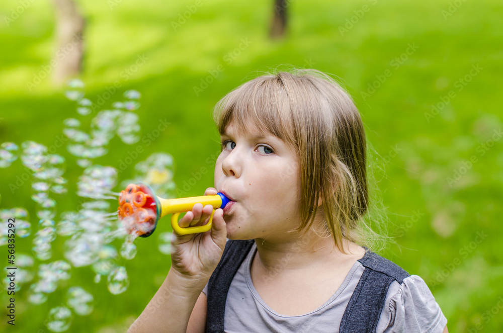 Little girl playing with soap bubbles in summer park Little girl playing with soap bubbles in summer park