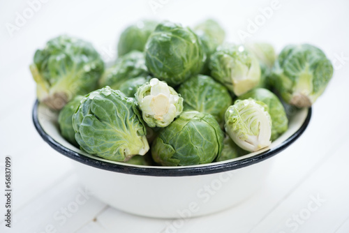 Bowl with fresh brussels sprouts on white wooden boards
