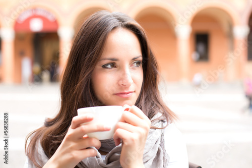 Beautiful young girl drinking a cup of coffee on a summer day
