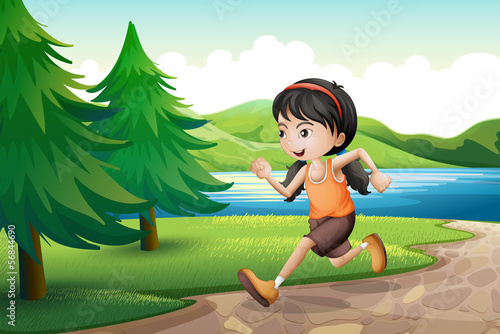 A girl running near the riverbank with pine trees