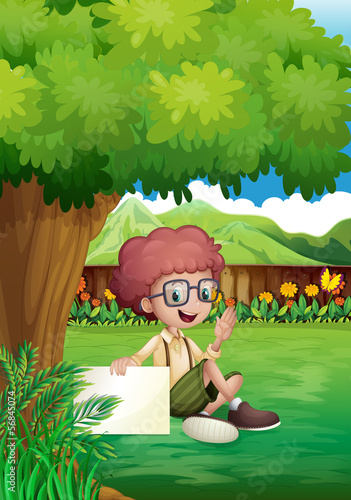 A young boy under the tree with an empty signage