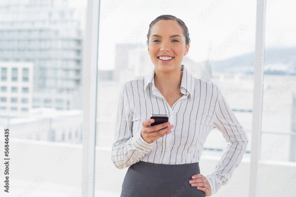 Happy businesswoman standing in her office and texting Happy businesswoman standing in her office and texting