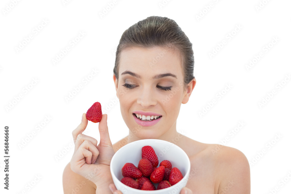 Gorgeous natural brown haired model showing a bowl of strawberri Gorgeous natural brown haired model showing a bowl of strawberri