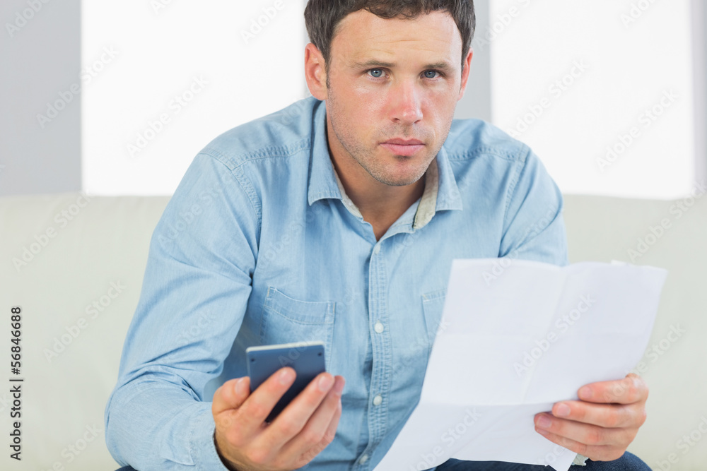 Serious casual man holding calculator and document Serious casual man holding calculator and document