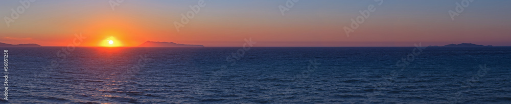 Panoramic shot of beautiful coastal sunset with some islands on