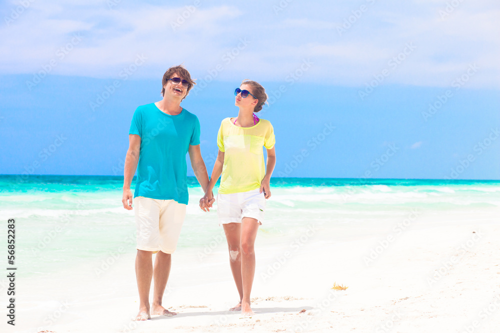Couple walking and having fun on a tropical beach at Maldives Couple walking and having fun on a tropical beach at Maldives