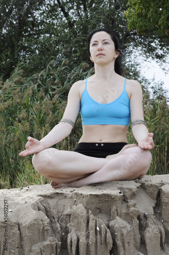 Woman sitting in lotus position on a sand cliff