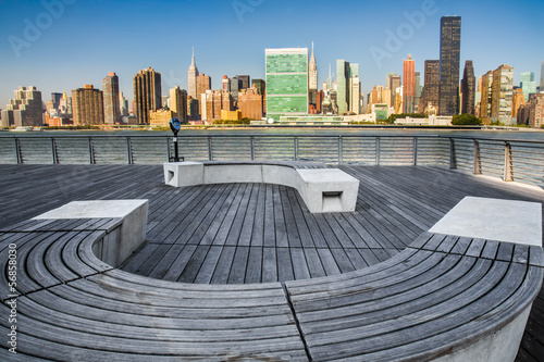 Modern wooden bench at park with view of New York City skyline