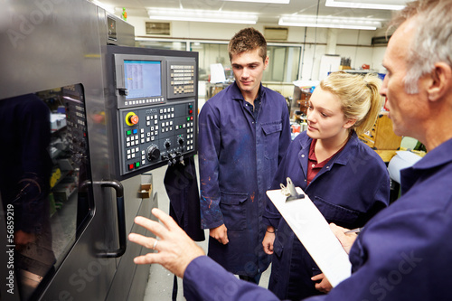 Engineer Teaching Apprentices To Use Computerized Lathe