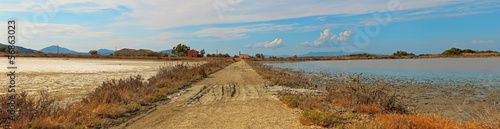 Panoramic shot of dirt road in salt flats with blue cloudy sky.