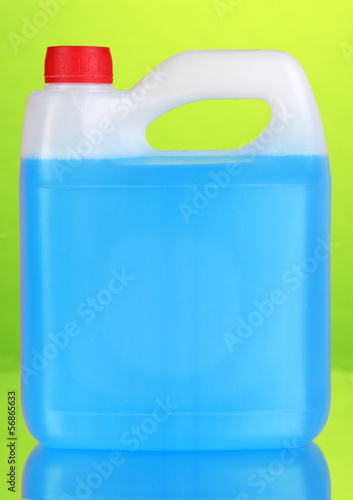 Blue liquid for car in canister on green background