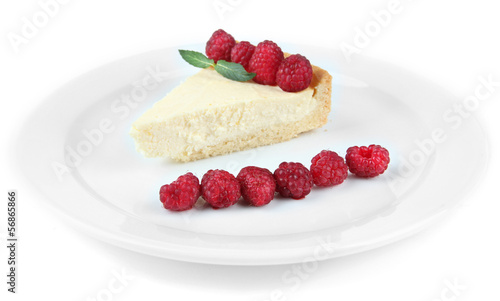 Slice of cheesecake with raspberry on plate, isolated on white