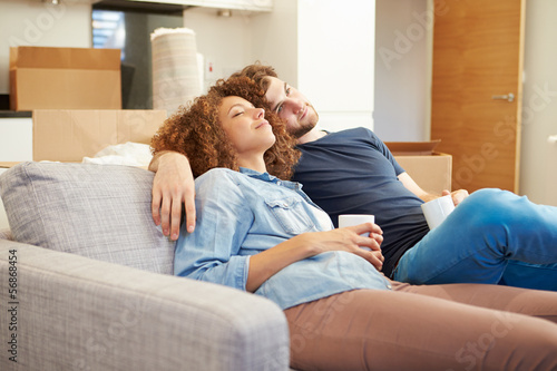 Couple Relaxing On Sofa With Hot Drink In New Home