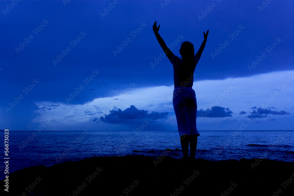 Fototapeta premium Silhouette of woman in the blue sky morning on sea beach rock
