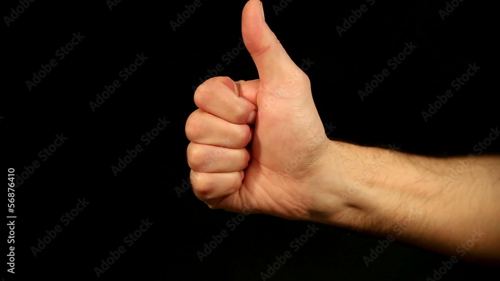 male hand lifts thumb up in front of an black background male hand lifts thumb up in front of an black background
