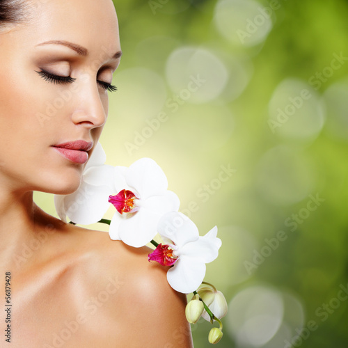Face of  beautiful woman with a white orchid flower