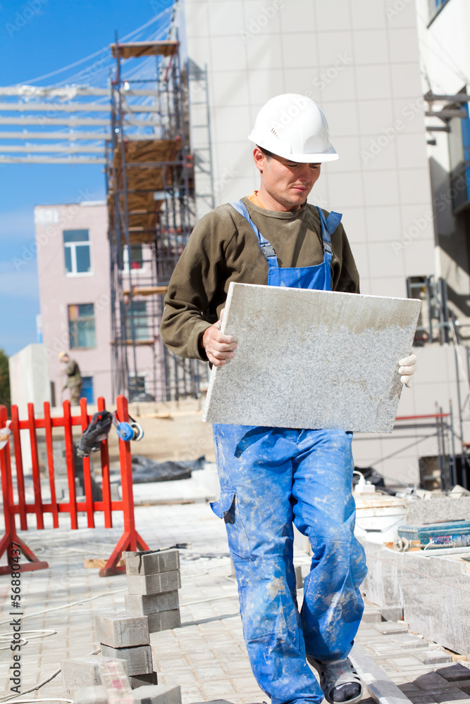 Tiler man with granite tile during construction works