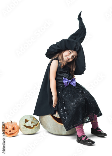 Fototapeta little witch sits on a pumpkin