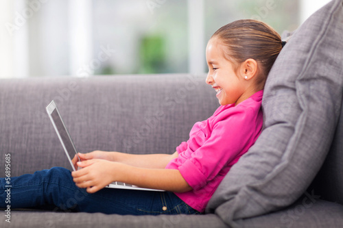 little girl using laptop on sofa