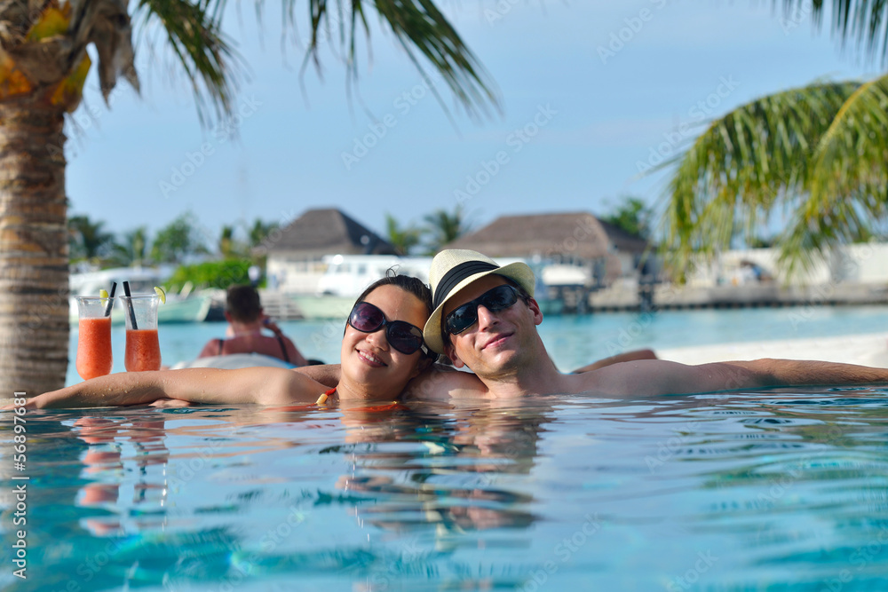 happy young couple relax and take fresh drink on poolside