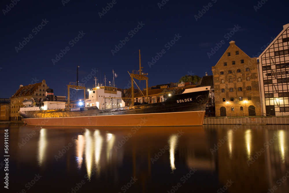 Reflections of the ship Soldek at night in the river Motlawa in