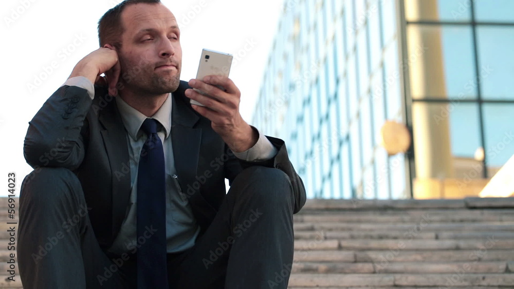 Bored young businessman sitting on stairs in the city Bored young businessman sitting on stairs in the city