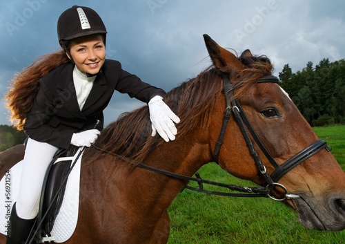 Beautiful smiling girl sitting on a horse outdoors