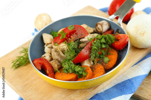 Sliced fresh vegetables in pan on wooden board isolated on