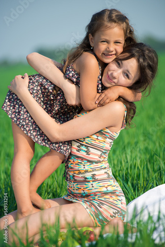 Tableau sur toile Happy girls on green grass. Playing