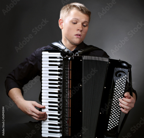 musician plays the accordion against a dark background