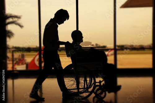 Asistente llevando en silla de ruedas a un viajero en la terminal de un aeropuerto photo