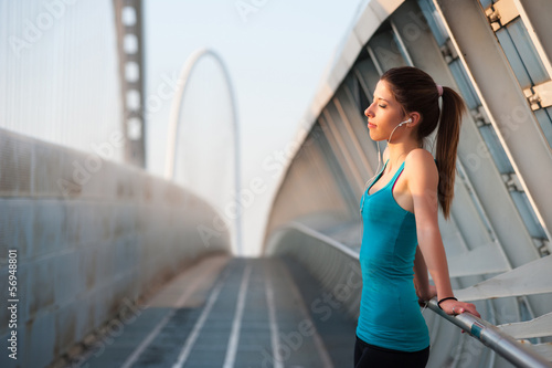 Young woman outdoors on a modern bridge while listening to music