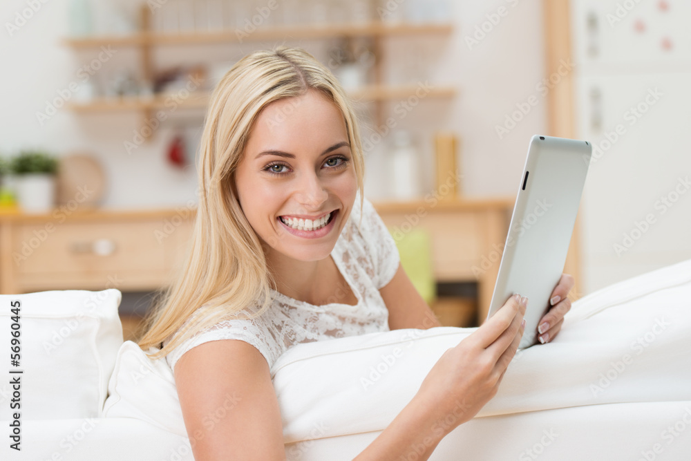 lächelnde junge frau liest tablet auf dem sofa lächelnde junge frau liest tablet auf dem sofa