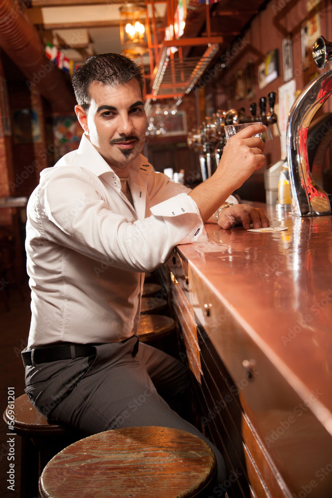 portrait of handsome man sitting in bar and holding glass