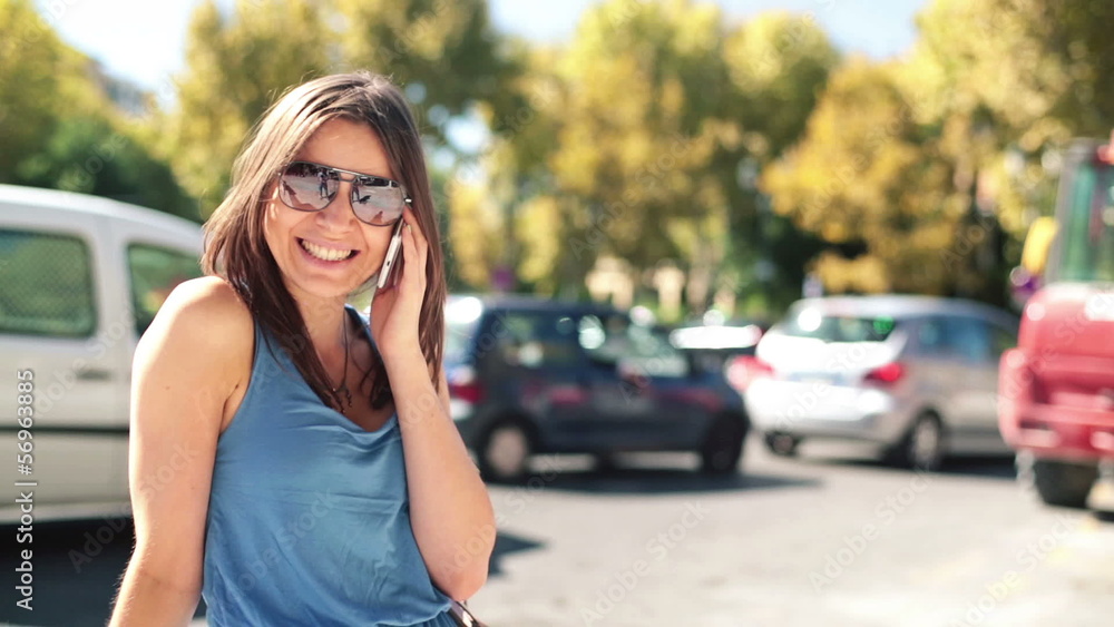 Happy attractive woman talking on cellphone by city street Happy attractive woman talking on cellphone by city street