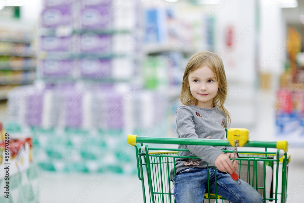 Adorable girl sitting in shopping cart