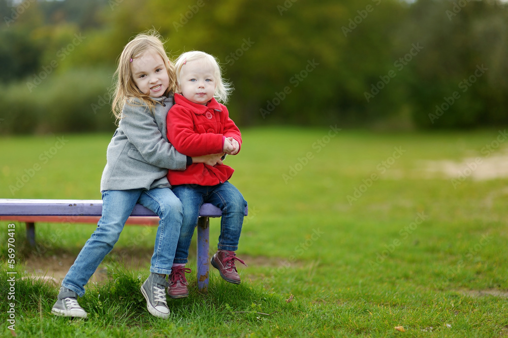 Two little sisters hugging on a bench Two little sisters hugging on a bench