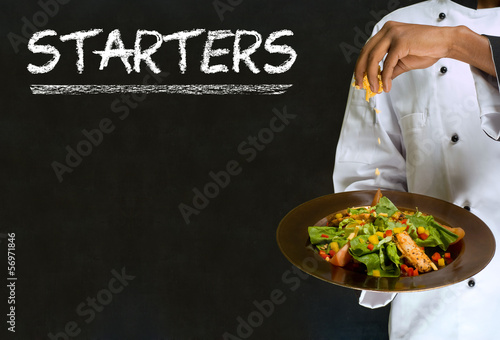 Chef with chalk starters sign on blackboard background